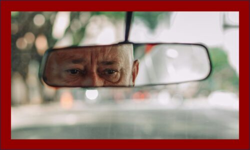 Old wise eyes seen in the rear view mirror from the back seat