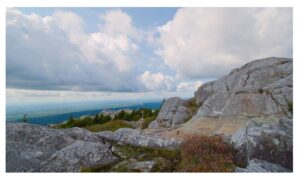 Gray Granite dome at Mount Monadnock summit with view of the green hills surrounding it.