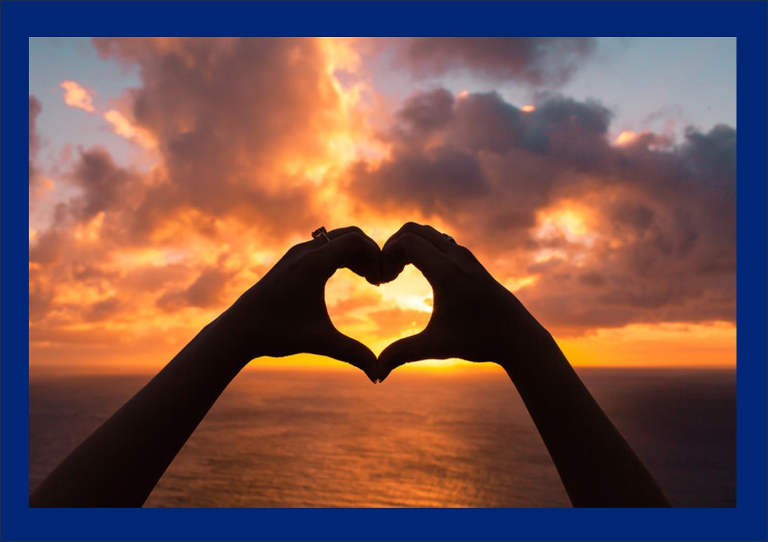 Sunset viewed through hands forming a heart shape -leading yourself from your heart.